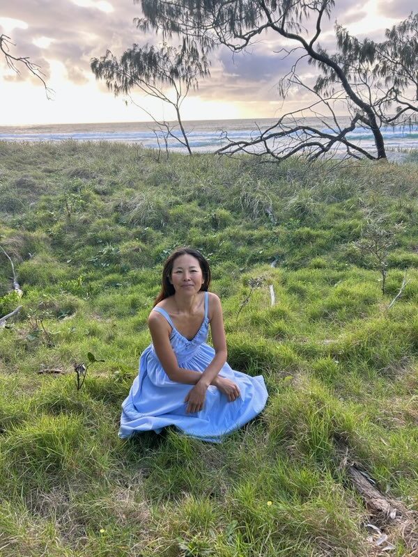Jun sitting on the grass by the coast